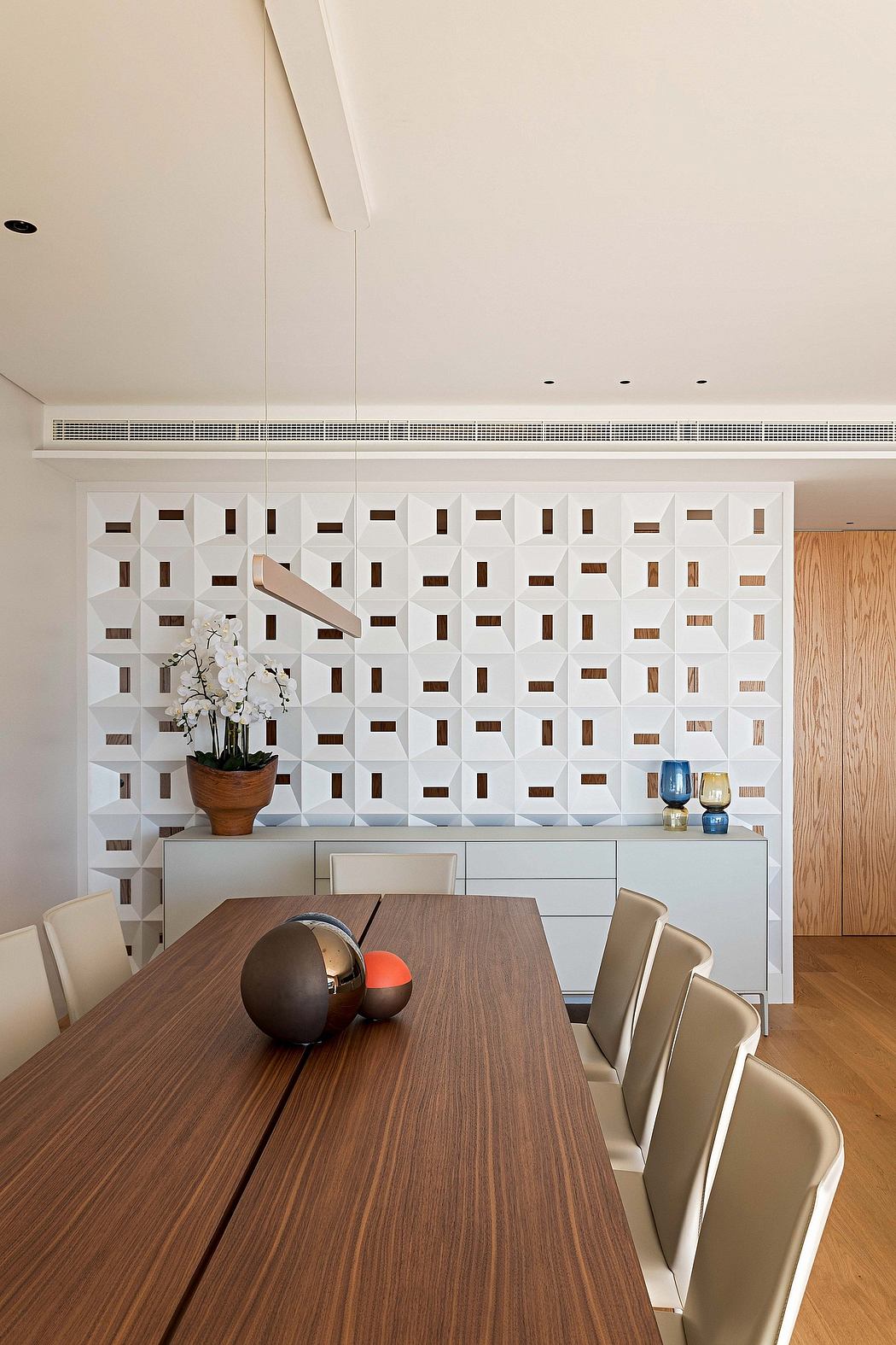 Contemporary dining room with geometric wall design and wooden table.