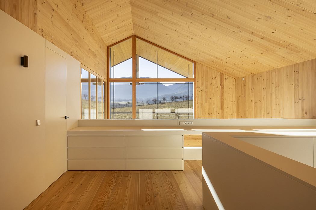 Minimalist interior with wooden walls, high ceiling, and large windows overlooking the countryside.