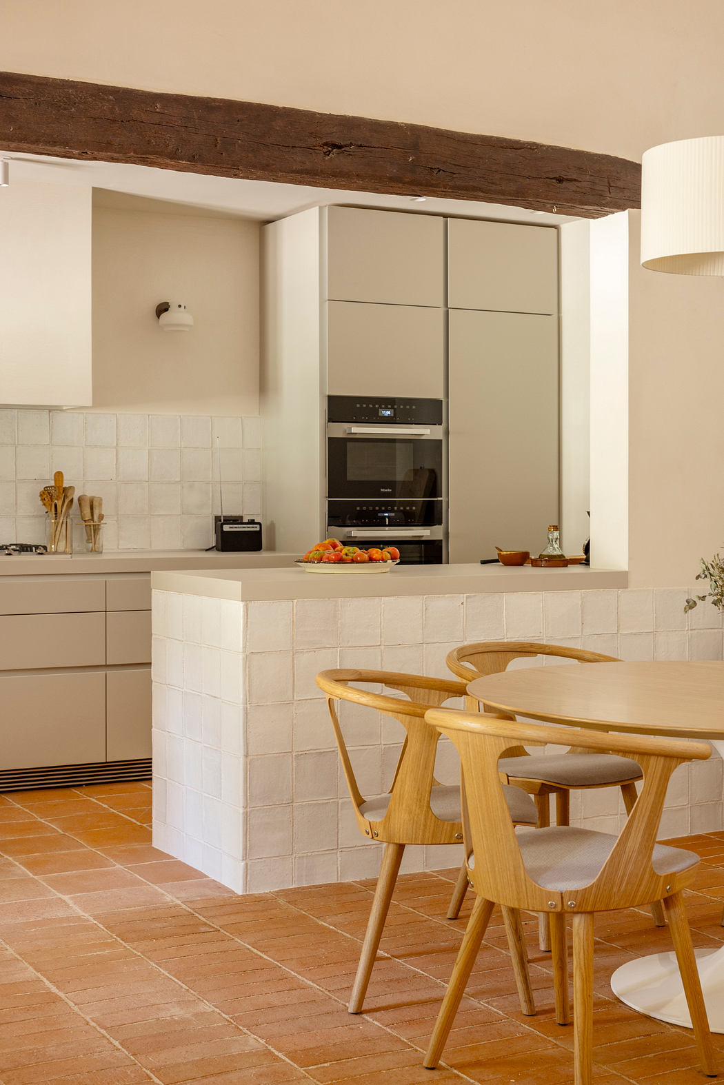Rustic kitchen with exposed wooden beams, modern cabinetry, and a wooden dining set.
