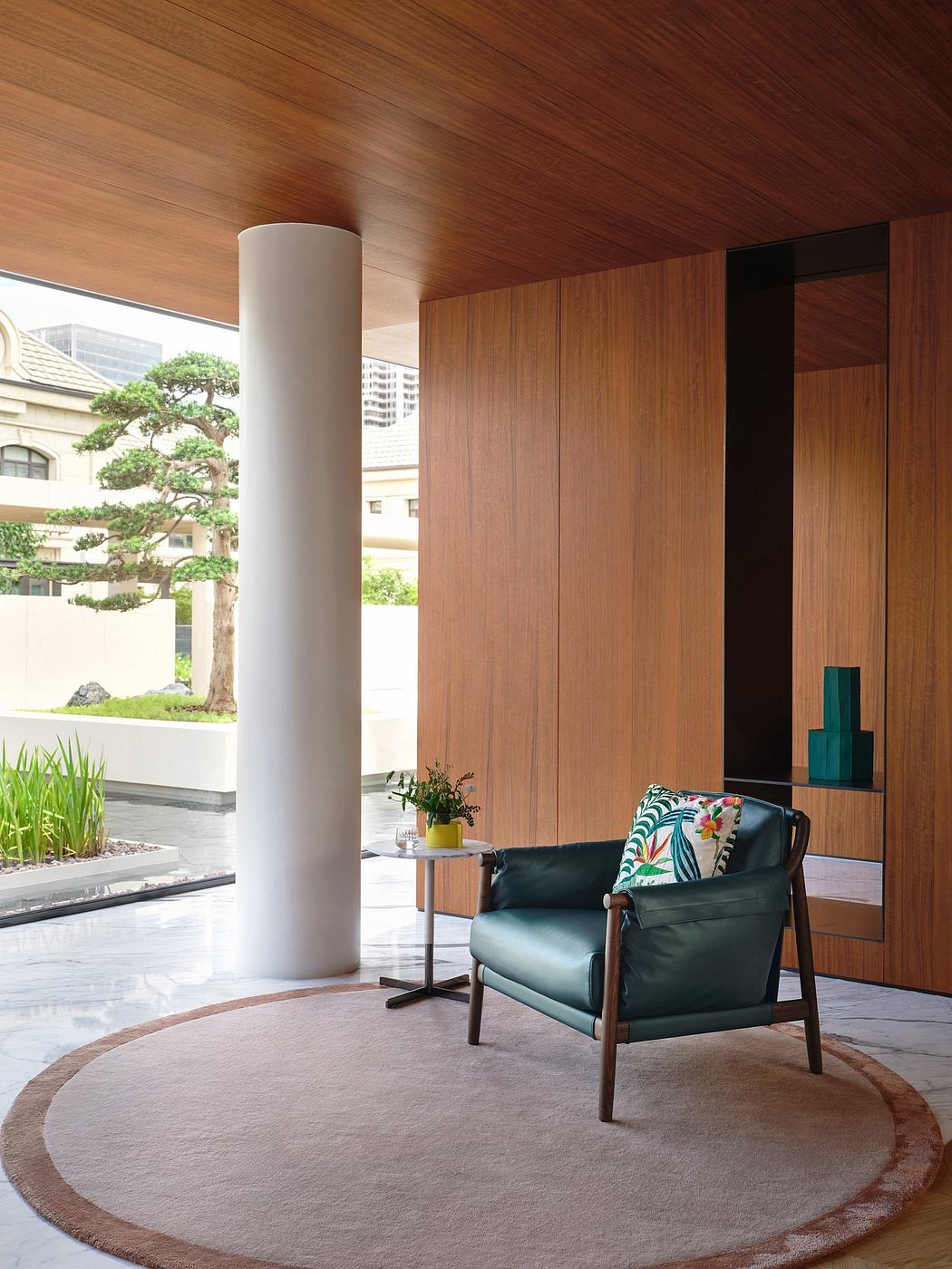 A modern interior with wood paneling, a plush green armchair, and a circular rug.