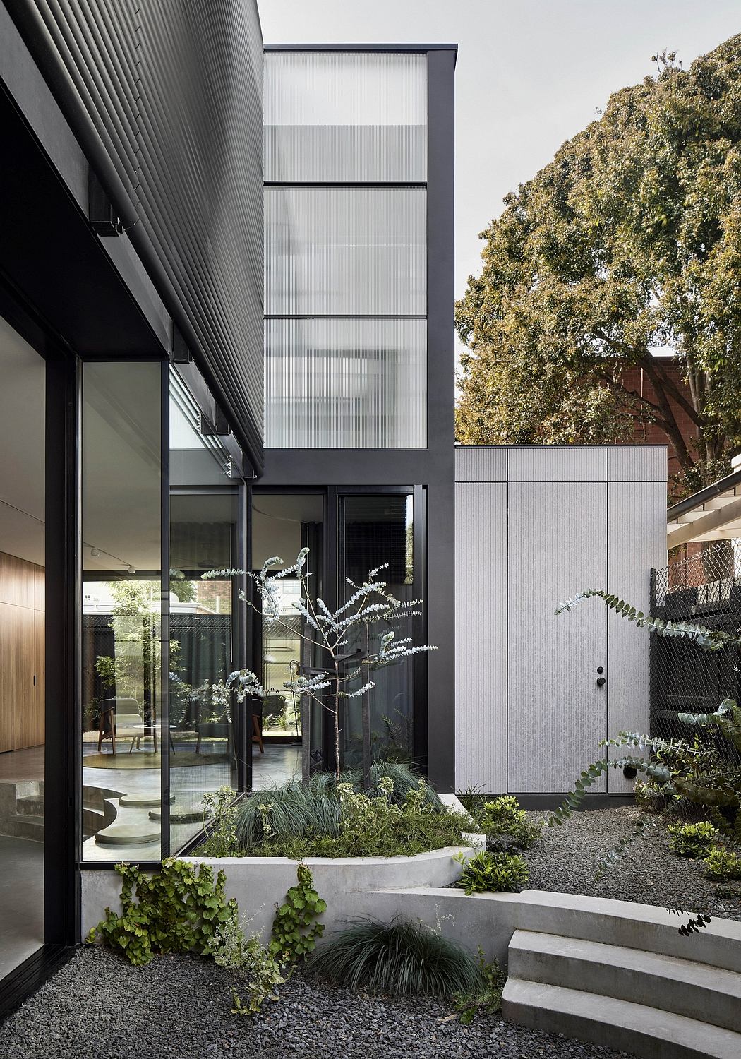 A modern architectural design featuring a glass facade, lush greenery, and minimalist landscaping.