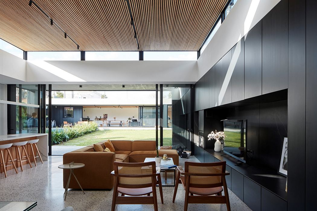 Sleek minimalist living space with wooden slatted ceiling and large windows.