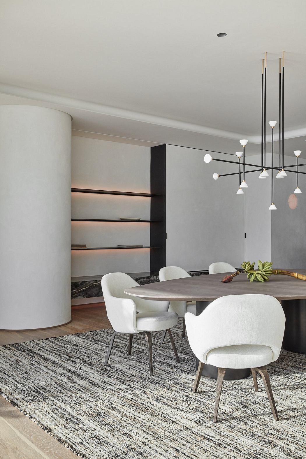 Minimalist dining room with sleek furniture, shelves, and modern chandelier.