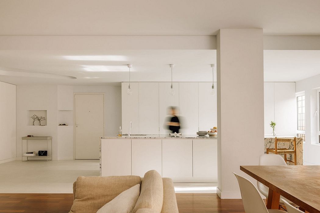 Open-concept living space with minimalist kitchen, wooden dining table, and natural lighting.