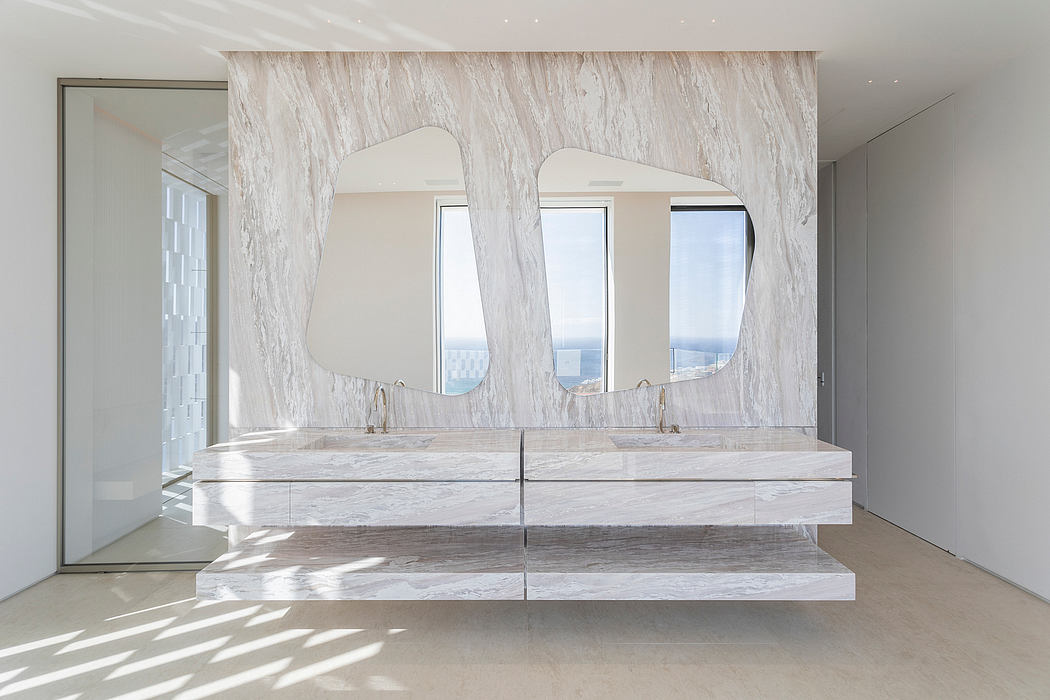Minimalist bathroom with twin marble sinks and unique mirror design.