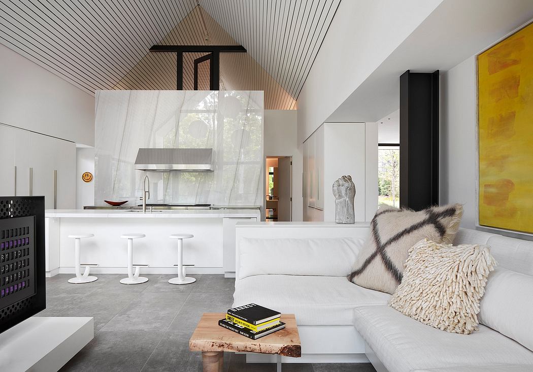 Modern living room with white sofa, kitchen bar, and yellow artwork.