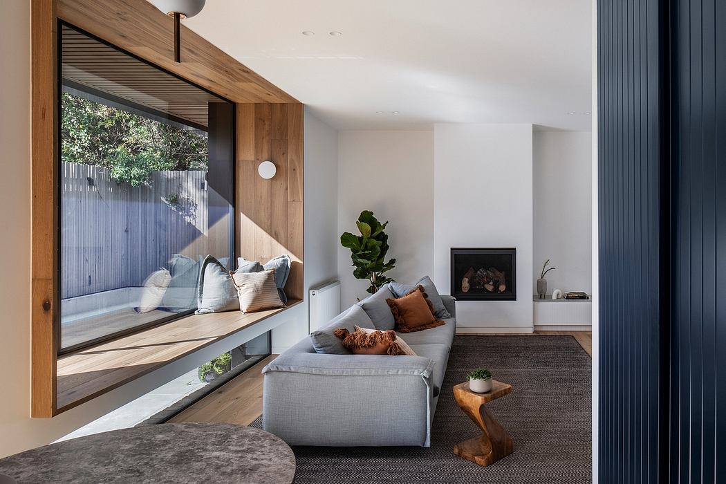 Modern living room with wooden accents, large grey sofa, and floor-to-ceiling windows.