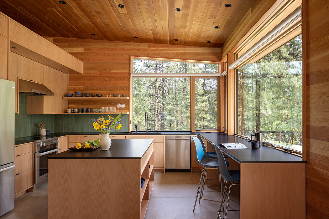 Wooden kitchen interior with large windows and forest view.