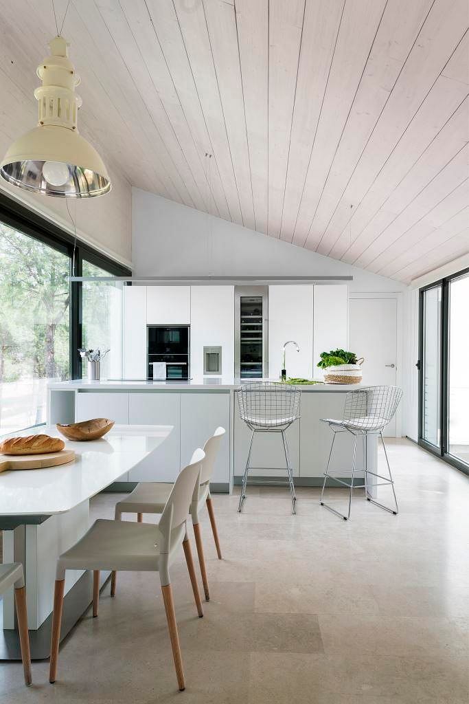 Sleek kitchen with white cabinetry, wooden ceiling, and minimalist decor.