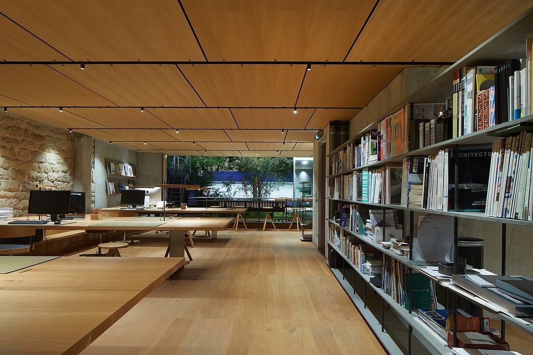 Rustic wood-paneled office space with bookshelves, desks, and natural lighting.