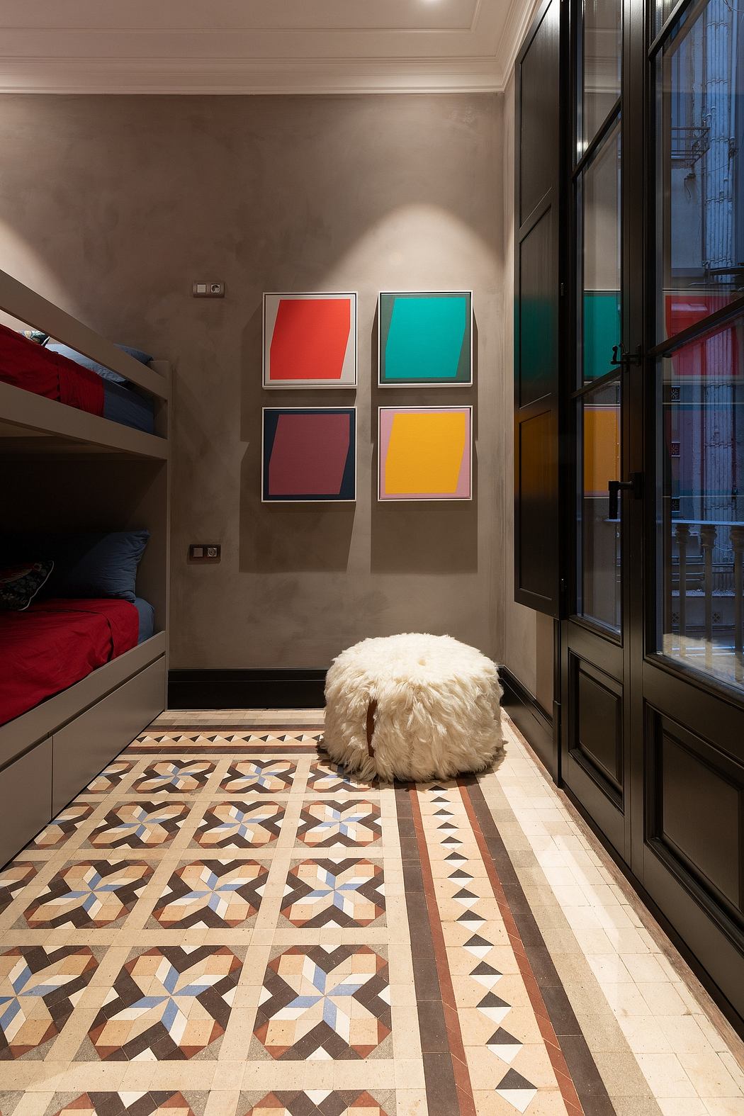 Modern hallway with colorful wall art, patterned floor, and fluffy stool.