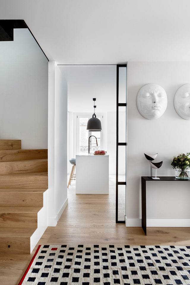 Contemporary home with wooden stairs, patterned rug, and chic minimalistic decor