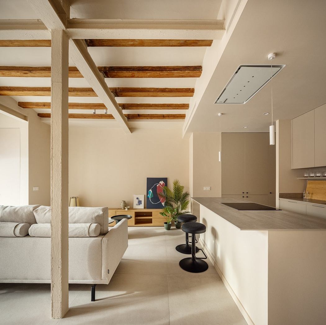 Warm, minimalist open-concept living space with exposed wooden beams, neutral tones, and modern furnishings.