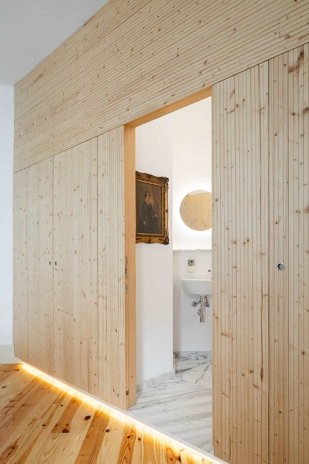 Contemporary wooden-paneled room with LED floor lighting.