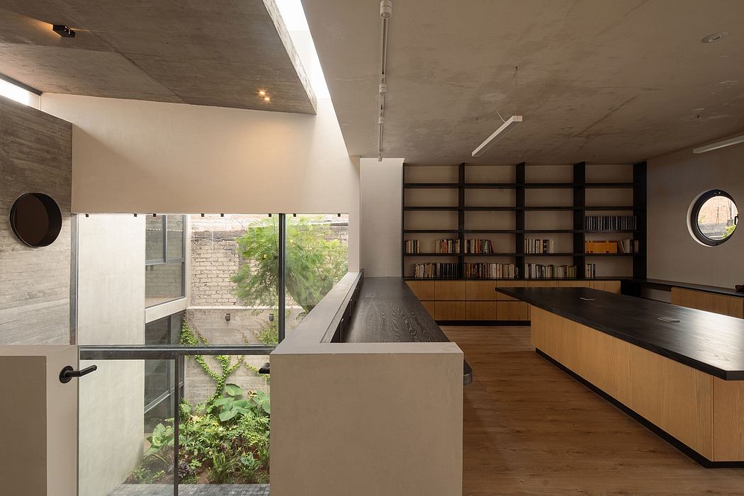 Modern interior with kitchen, bookshelves, and glass balcony overlooking a garden.