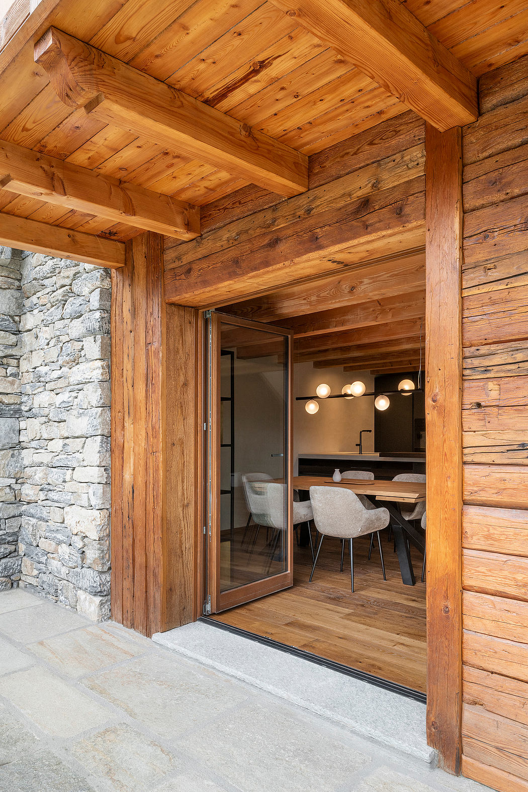Rustic wooden interior with stone wall, pendant lighting, and open dining area.