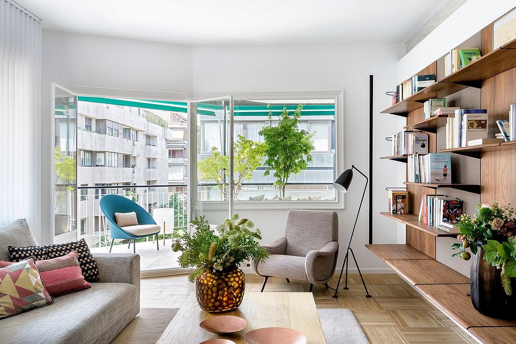 Cozy modern living room with large windows, bookshelves, and lush greenery.