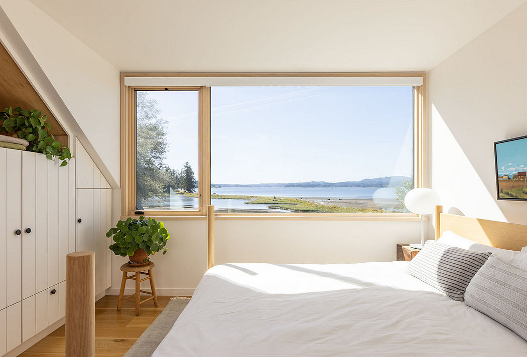 Bright minimalist bedroom with large window overlooking water.