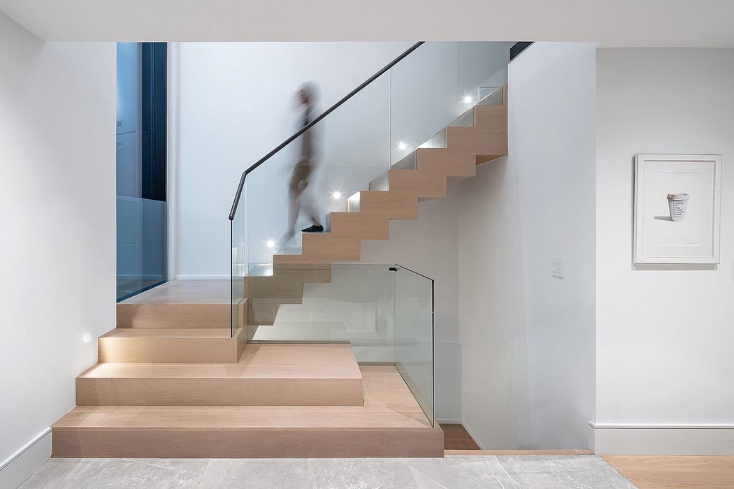 Minimalist staircase with glass railing and wood steps.