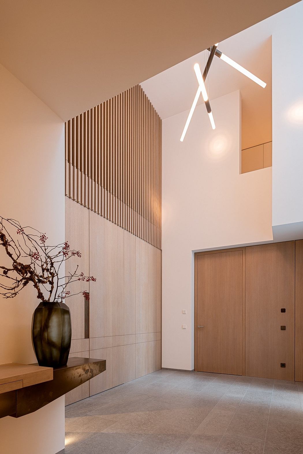 Sleek, modern entryway with wooden slat feature wall, minimalist lighting, and decorative vase.