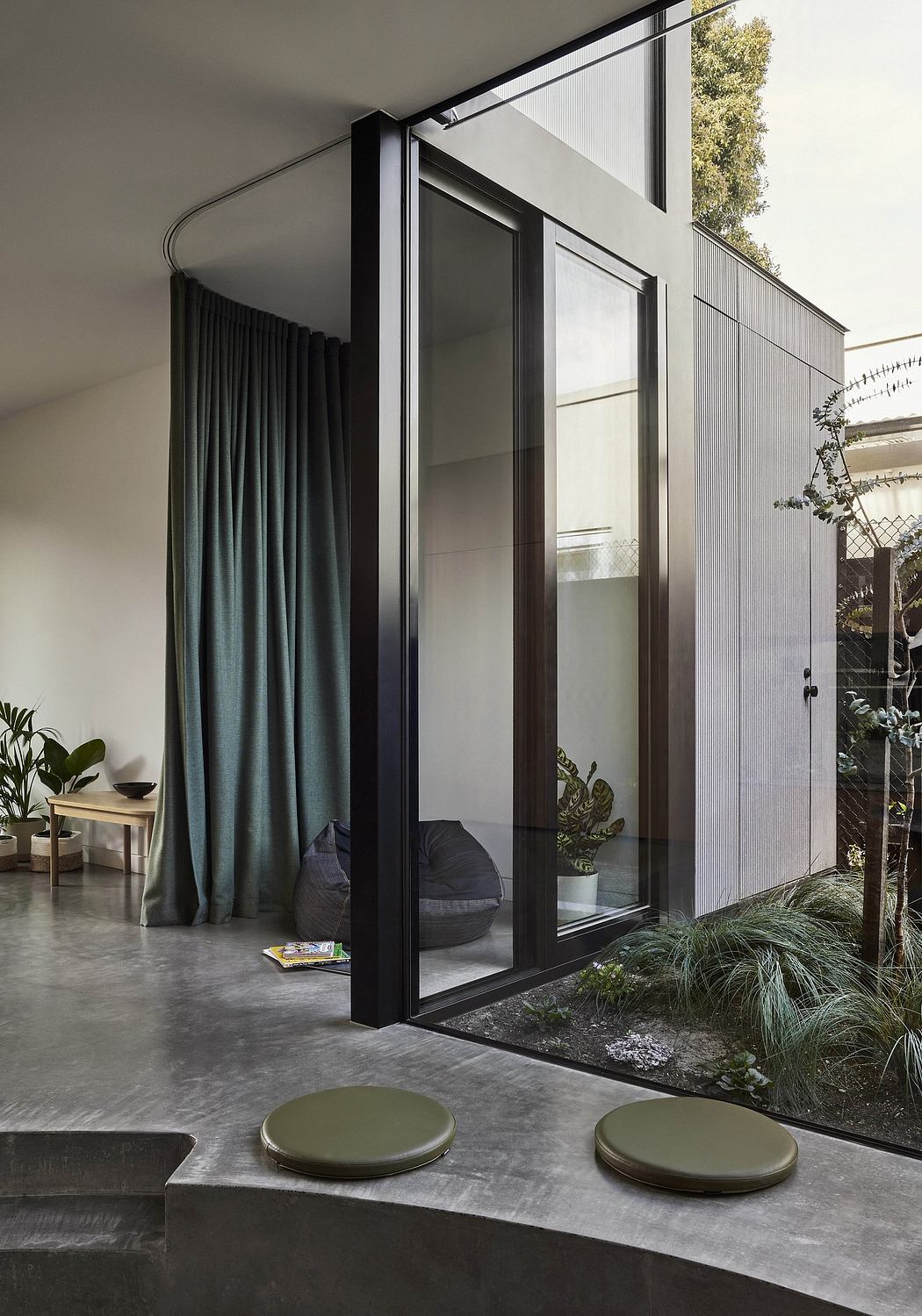 Expansive glass wall overlooking a lush, verdant outdoor space, with modern furnishings.