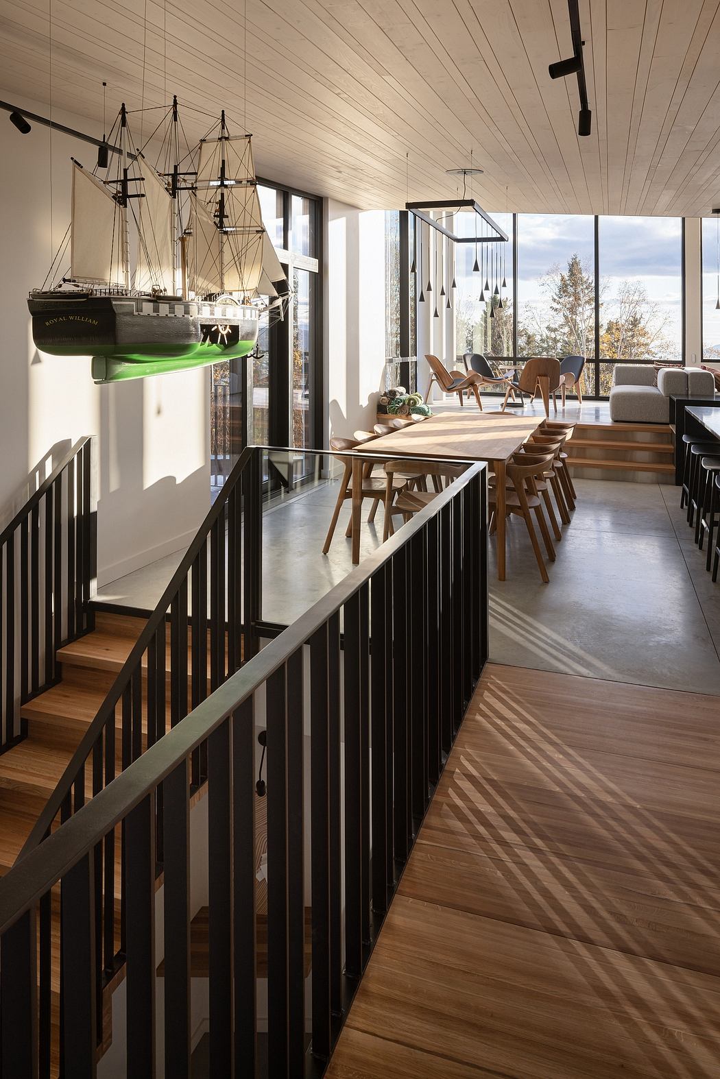 Contemporary interior with wooden floors, sleek railings, and ship model, leading