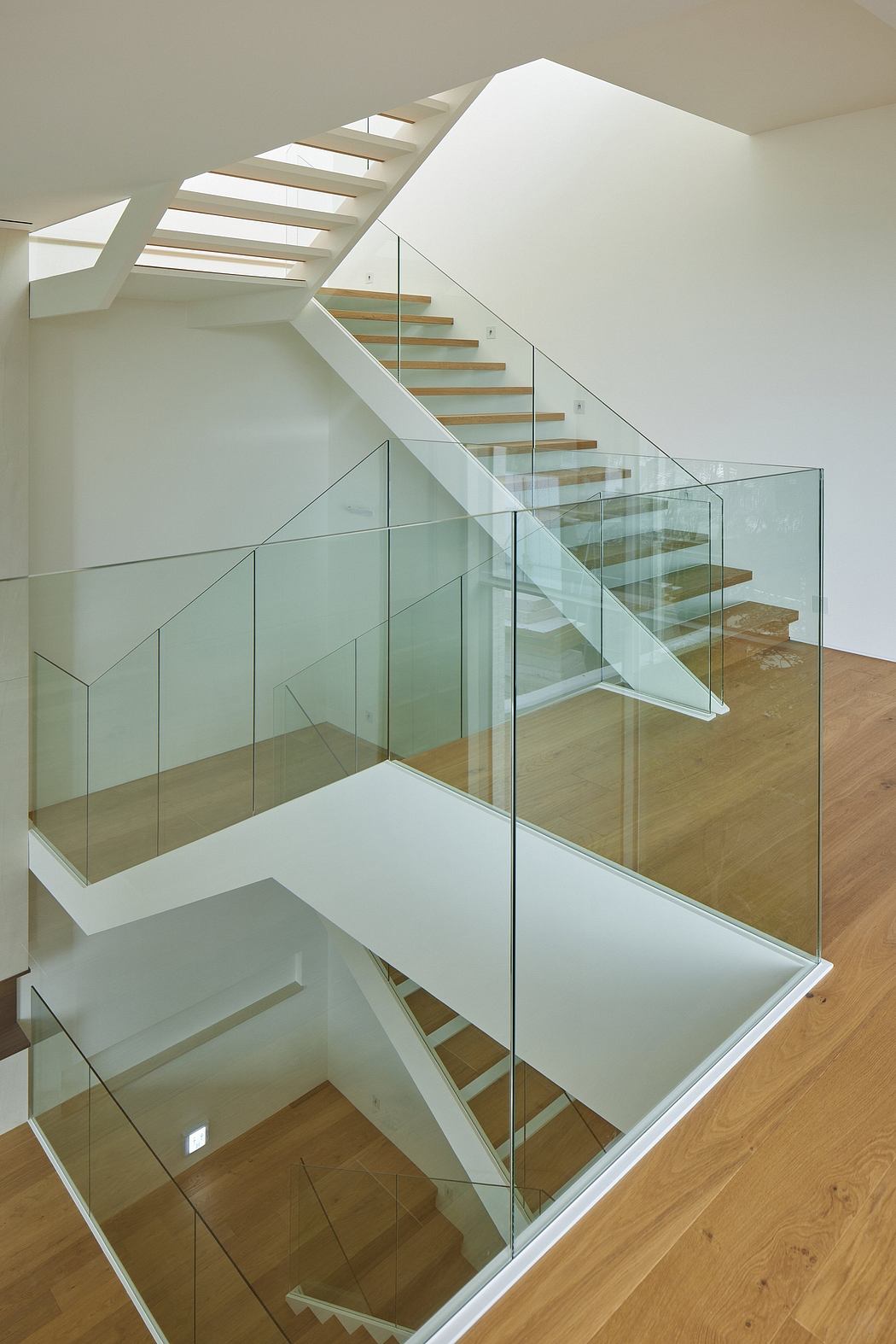Modern staircase with glass balustrades and wooden steps.