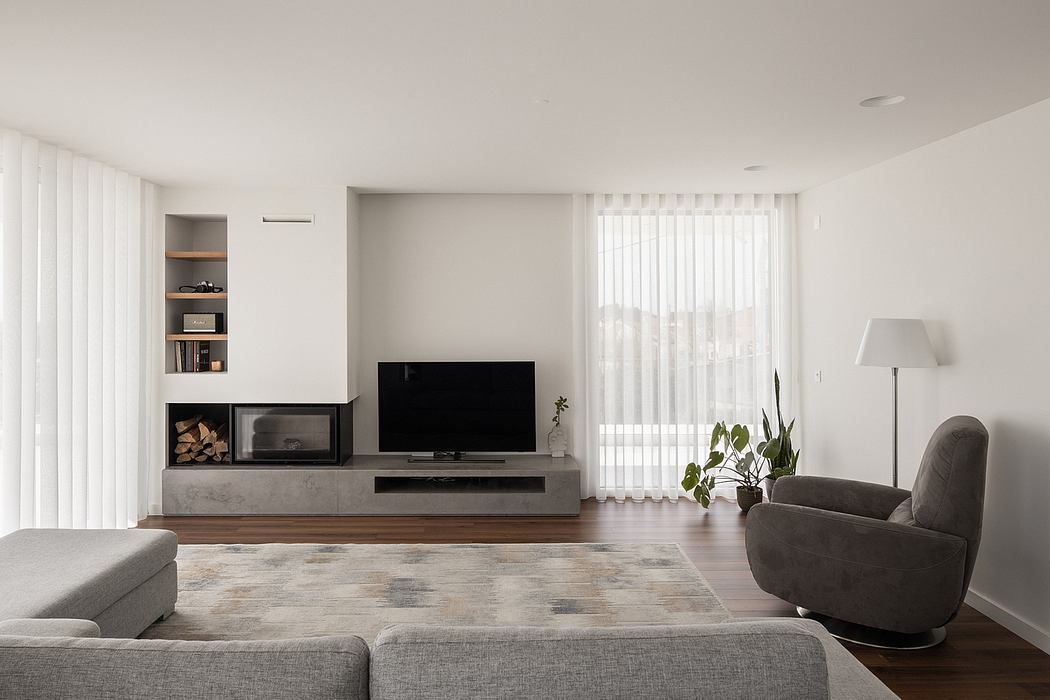 Minimalist living room with gray sofa, TV console, and potted plant by window. Sleek, modern design.