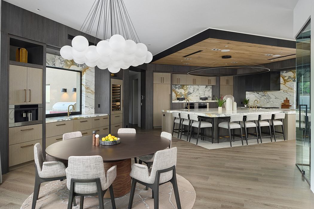 A modern, high-end kitchen and dining room with sleek cabinetry, marble countertops, and a dramatic cloud-like pendant light.