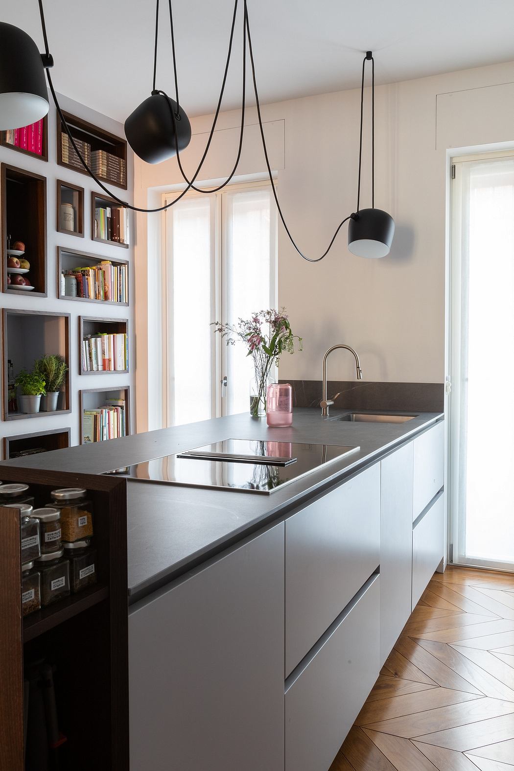 Modern kitchen with hanging lights, white cabinetry, and a bookshelf.