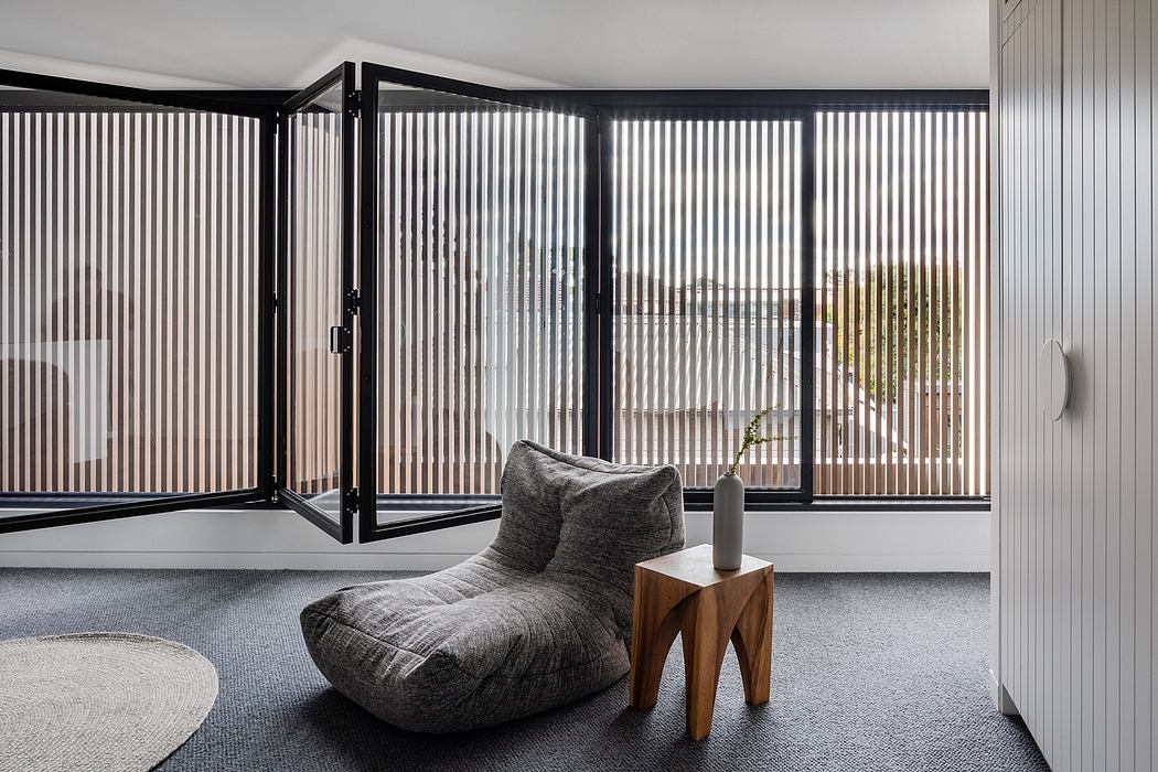 Modern living room with large windows, striped curtains, and a gray upholstered chair.