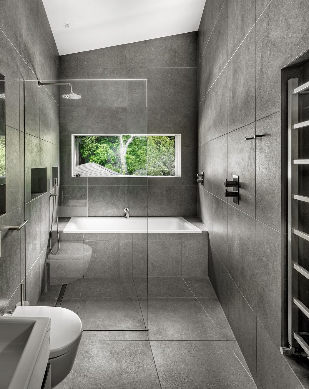 Sleek, modern bathroom with large window offering views of lush greenery outside.