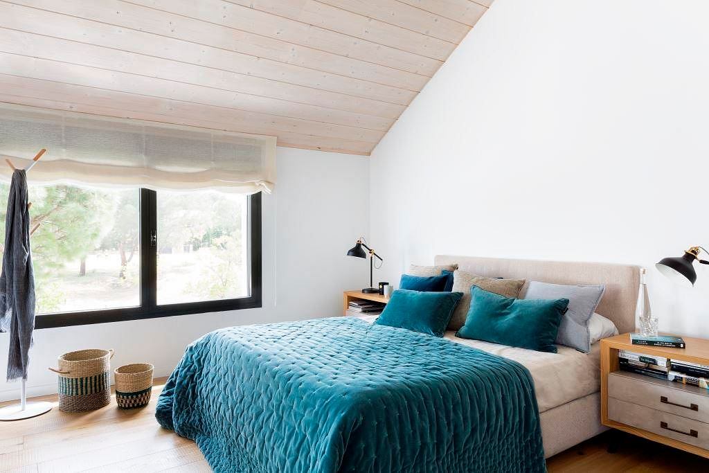 Bright bedroom with slanted ceiling and blue bedding.