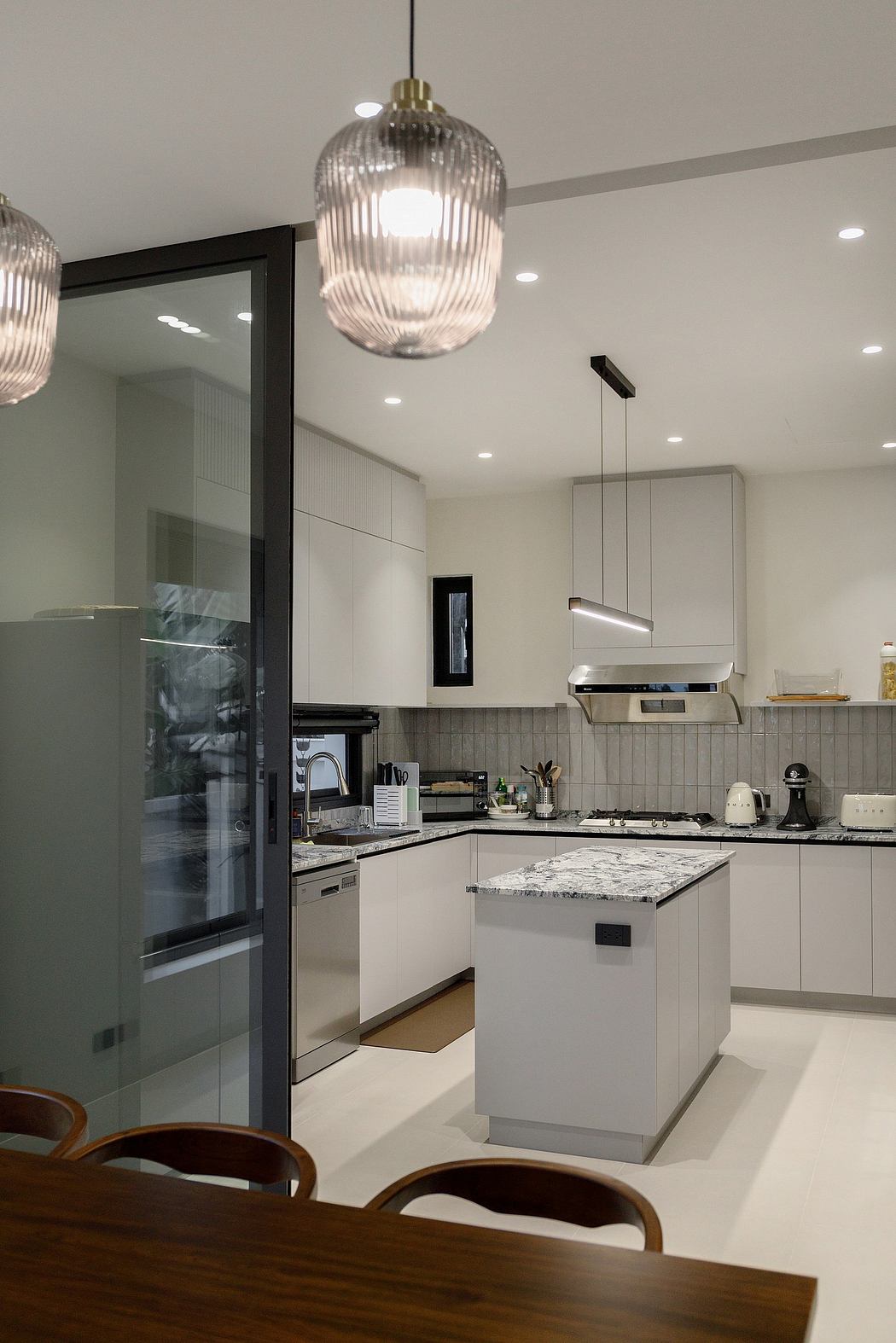 Modern kitchen interior with island, pendant lights, and dining area.