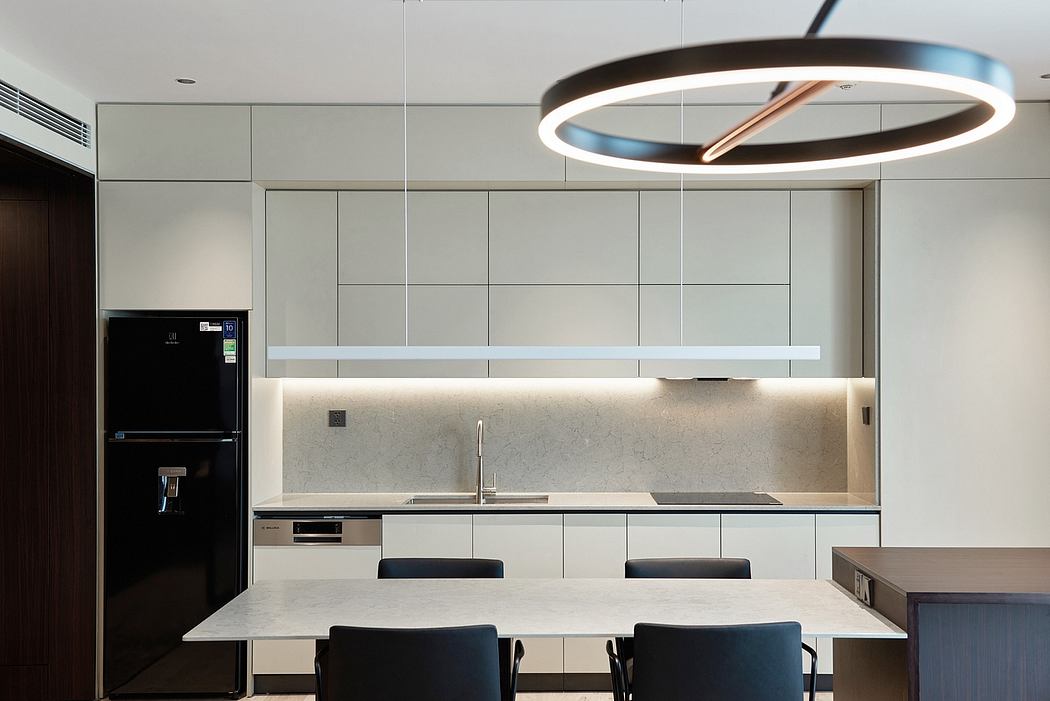 Modern kitchen interior with sleek gray cabinets, marble countertop, and a large circular lighting fixture.