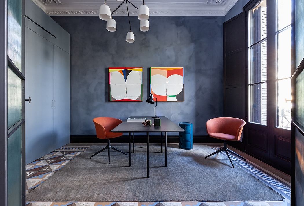 Modern office with gray walls, abstract art, and two red chairs.