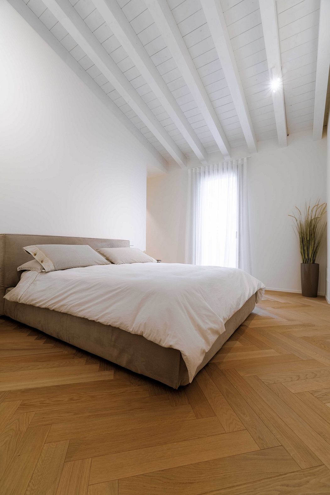 Minimalist bedroom with a white ceiling, herringbone floor, and neutral tones