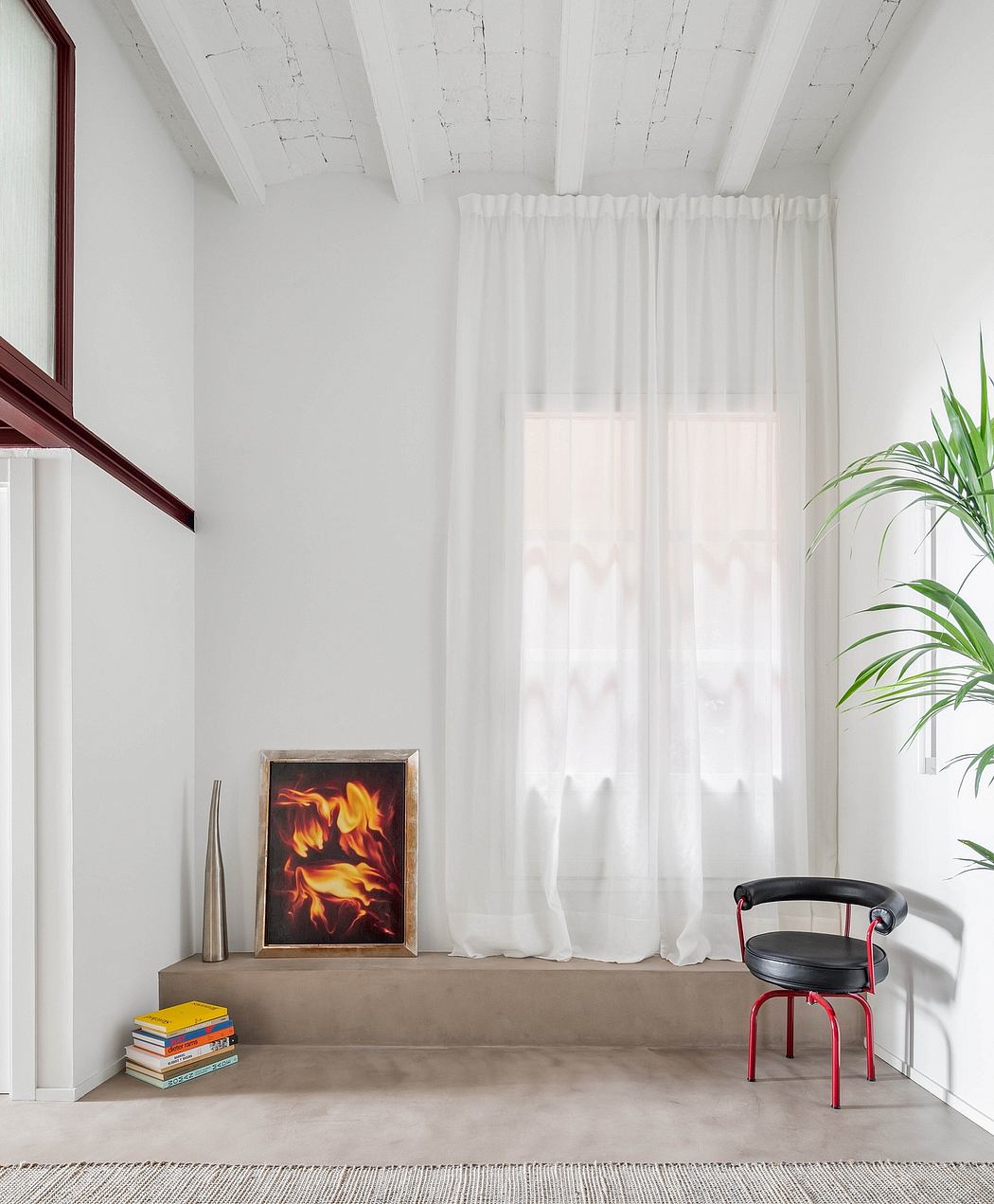 Minimalist room corner with sheer curtains, a plant, artwork, books, and