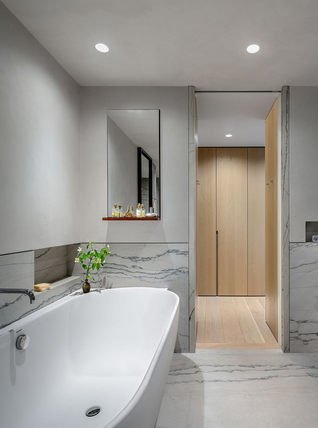 Elegant bathroom with freestanding tub, marble accents, and recessed lighting.