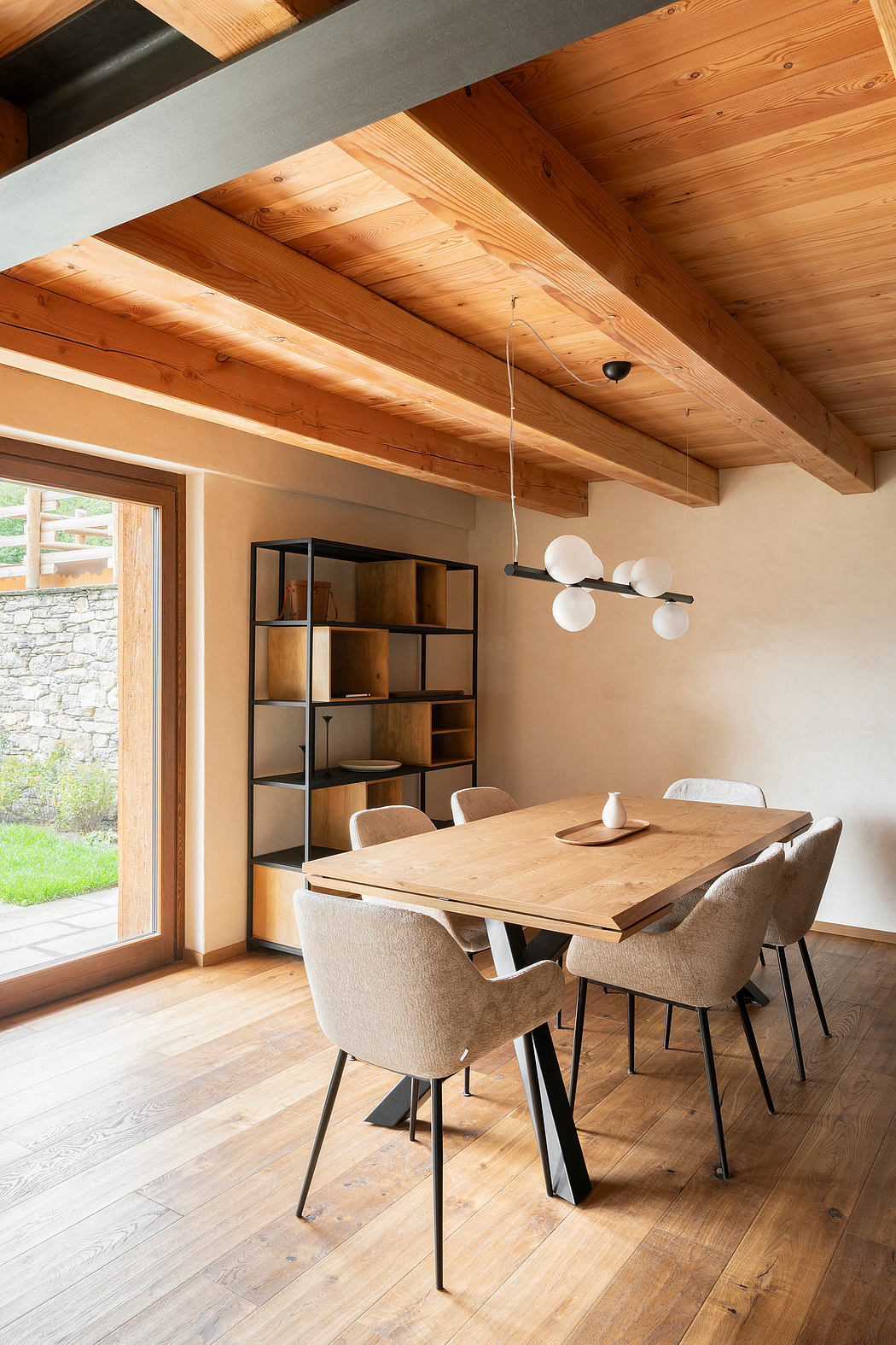 Warm, rustic interior with exposed wood beams, stone wall, and modern furniture.
