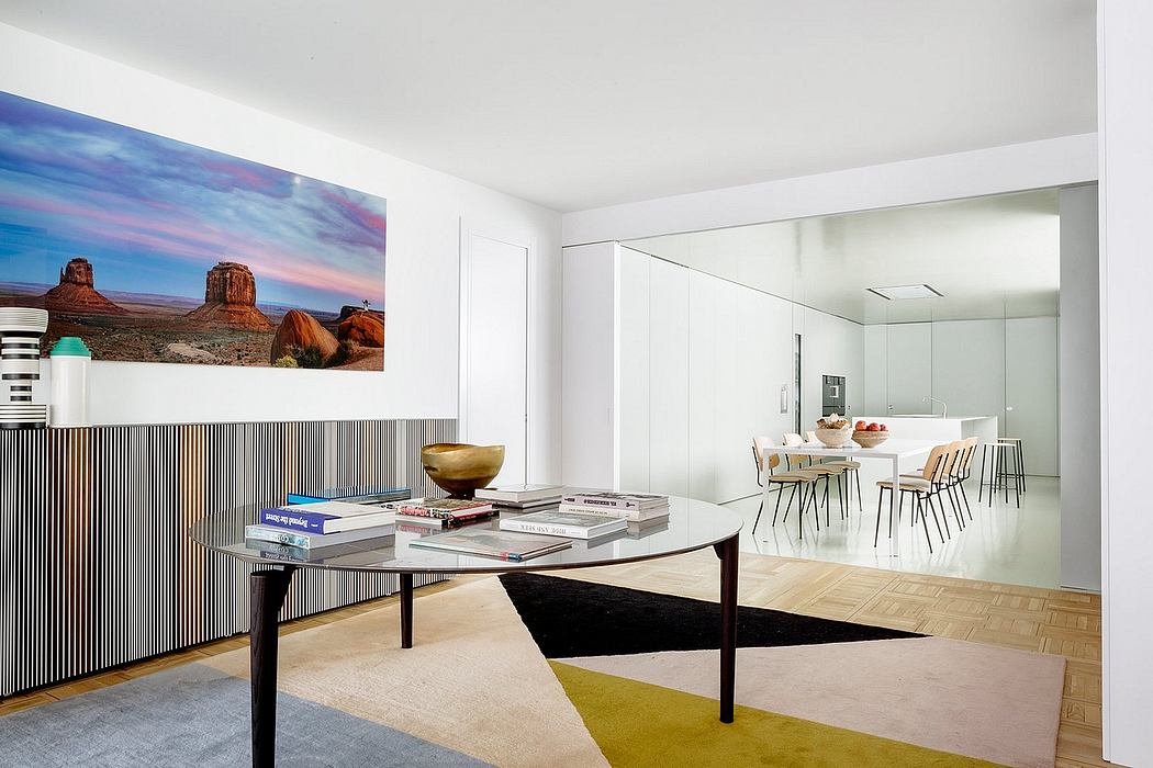 Modern, open-plan living space with large landscape artwork, glass walls, and geometric rug.