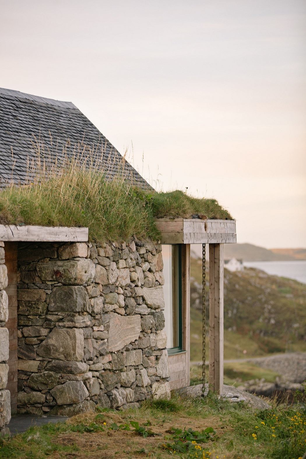 Stone cottage with a grass roof overlooking a coastal landscape.