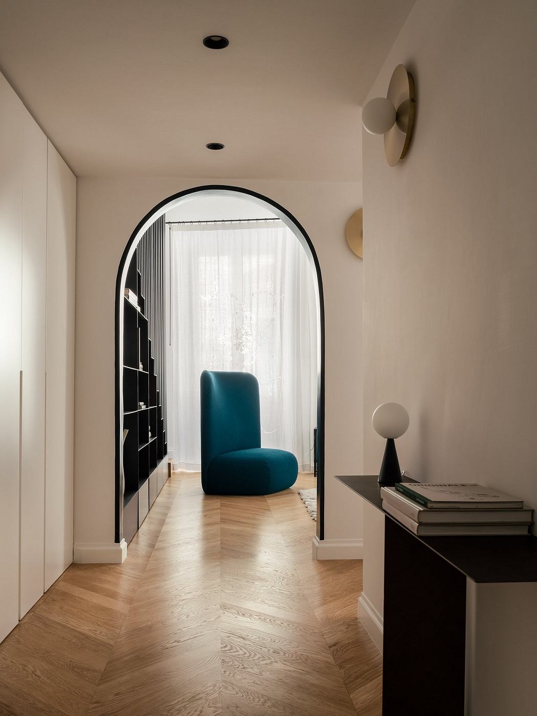 Sleek hallway with arched doorway and teal accent chair.