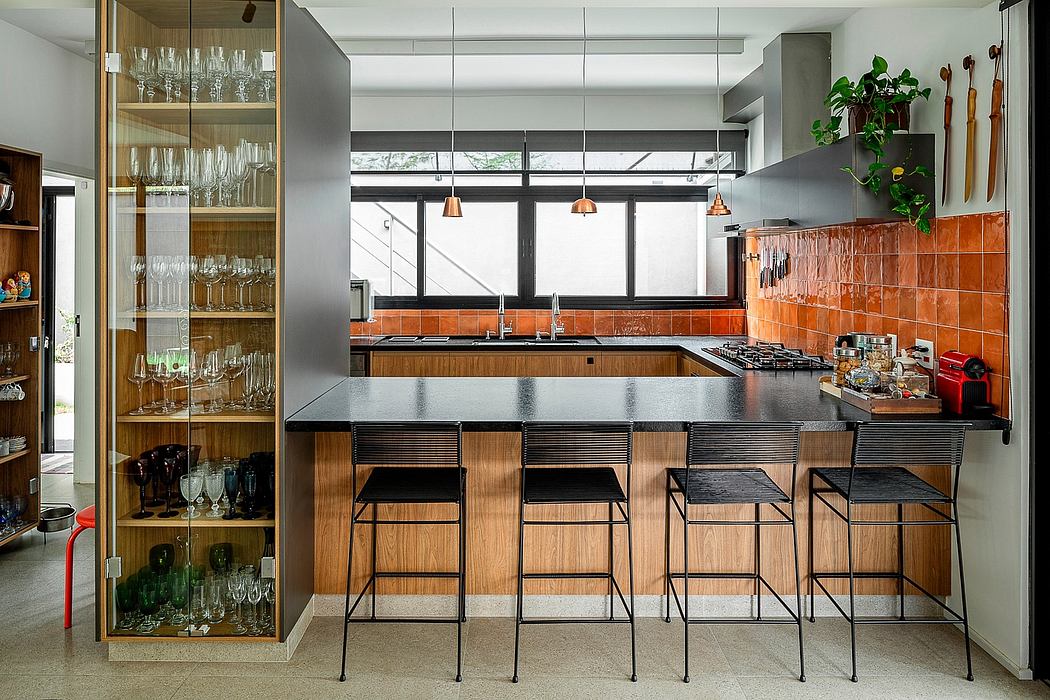 Modern kitchen with orange tiles, bar stools, and hanging lights.