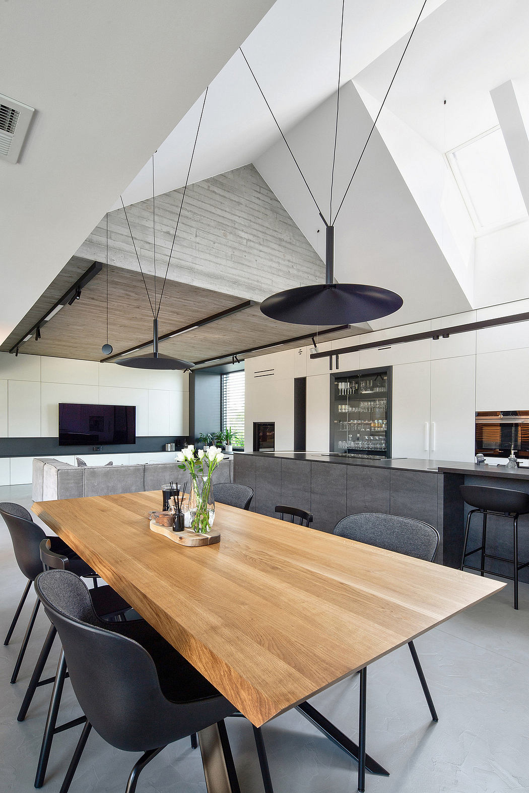 Modern kitchen with wooden dining table, black chairs, and unique pendant lighting.