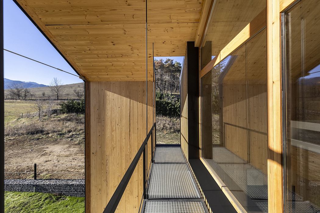 Wooden cabin exterior with glass windows, suspended walkway, and scenic mountain view.
