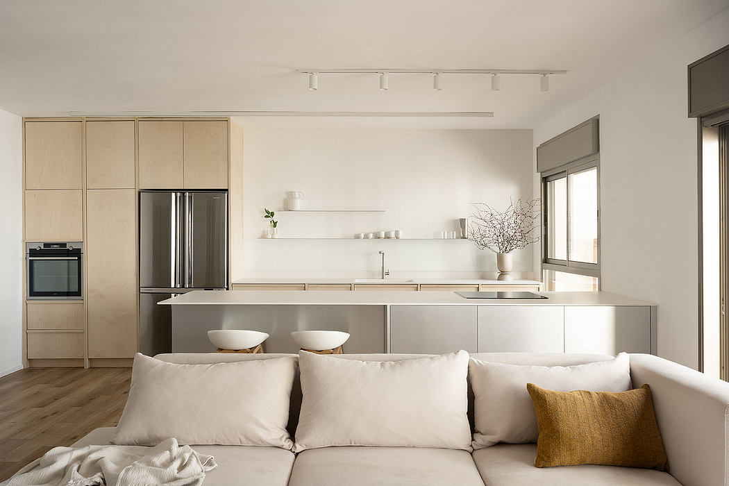 Modern kitchen with beige cabinets, white countertops, and adjacent living area with a sofa