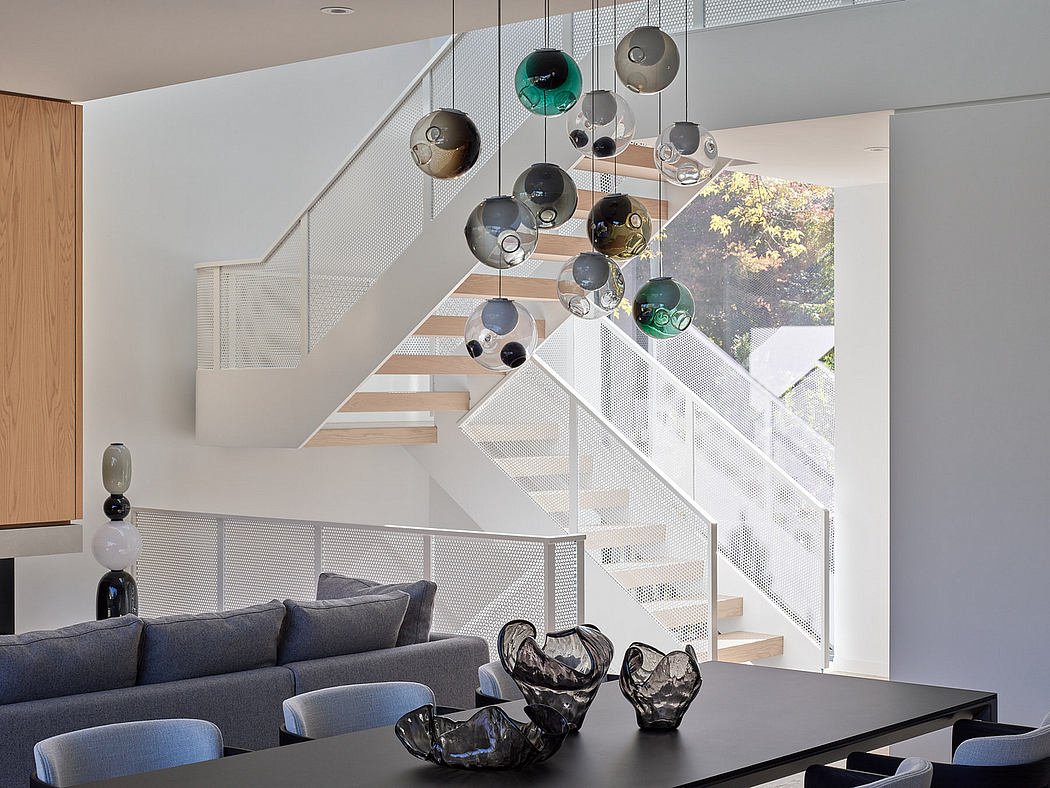 Modern interior with staircase and hanging glass pendant lights above dining table.