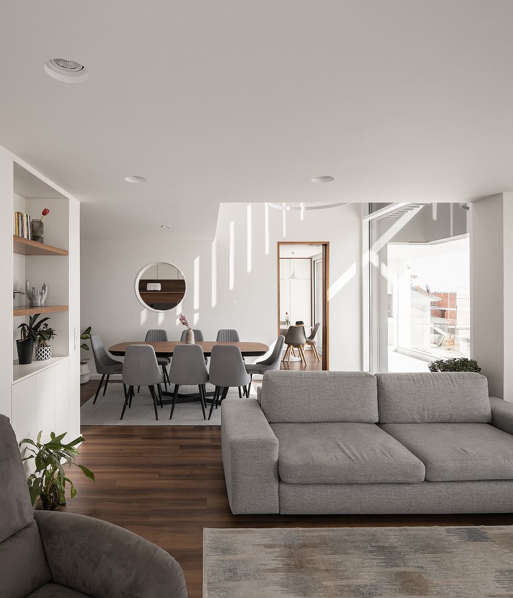 Modern, open-concept living area with sleek dining table, gray sofa, and natural lighting.