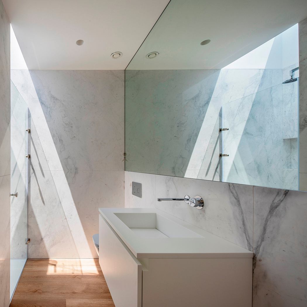 Sleek bathroom with marble walls and geometric skylights.